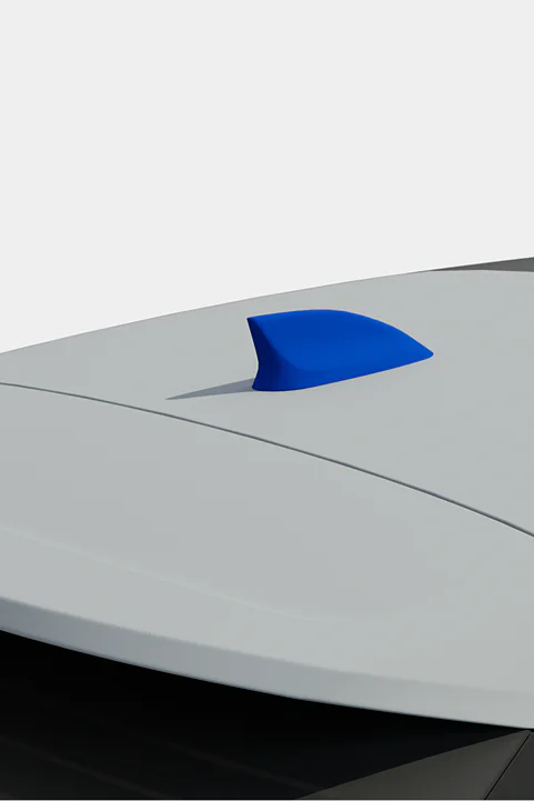 A blue shark fin antenna is mounted on the roof of a vehicle. The car is two-toned, with a gray roof and a darker section beneath. The antenna is centered and contrasts with the lighter color of the roof. The background is plain and unobtrusive. (This text has been generated by AI)